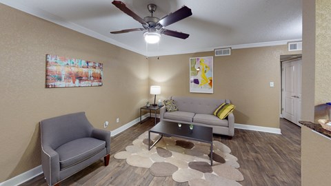 a living room with couches and a ceiling fan